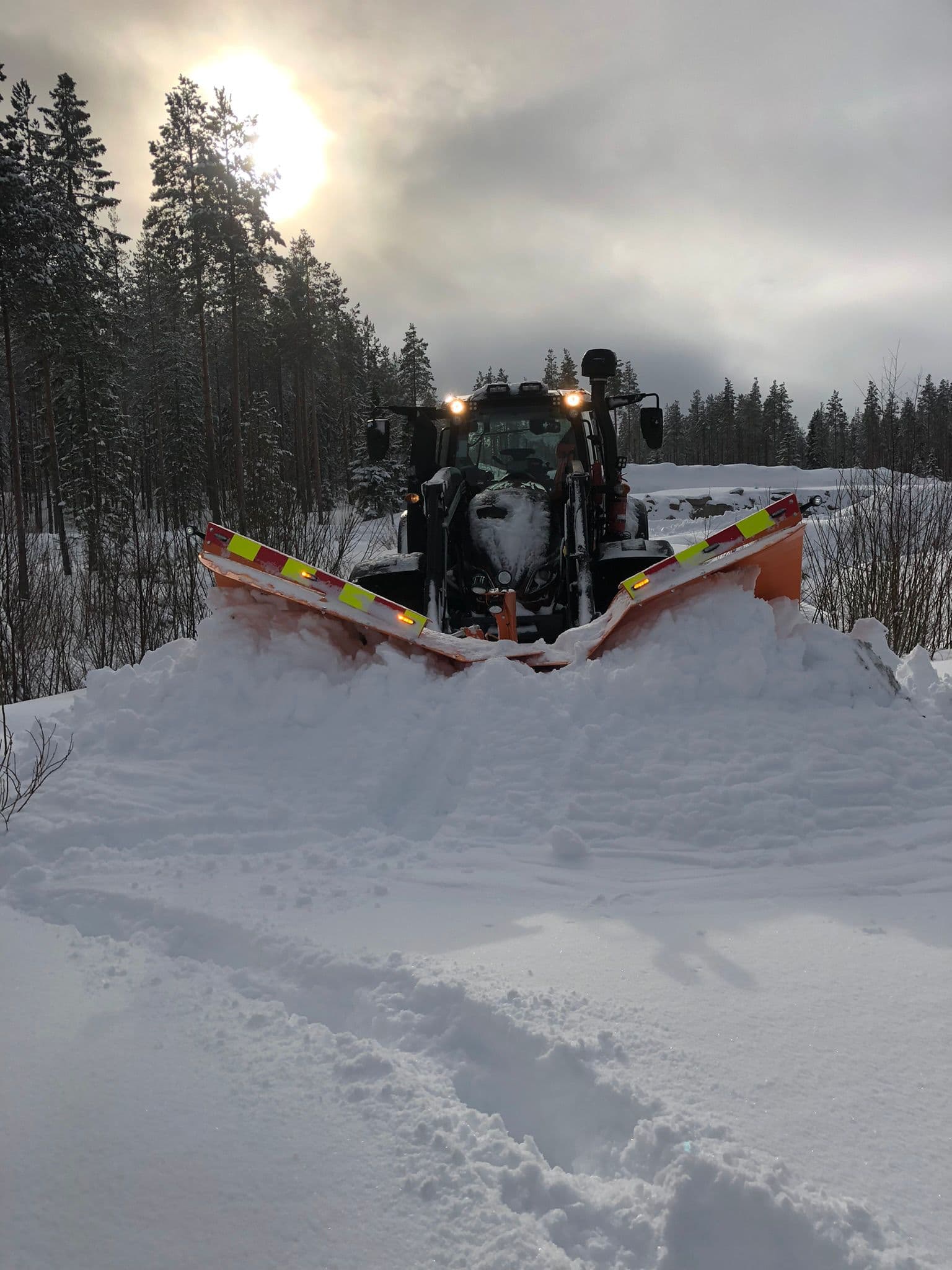 Traktori ja lumiaura lumisella tiellä.