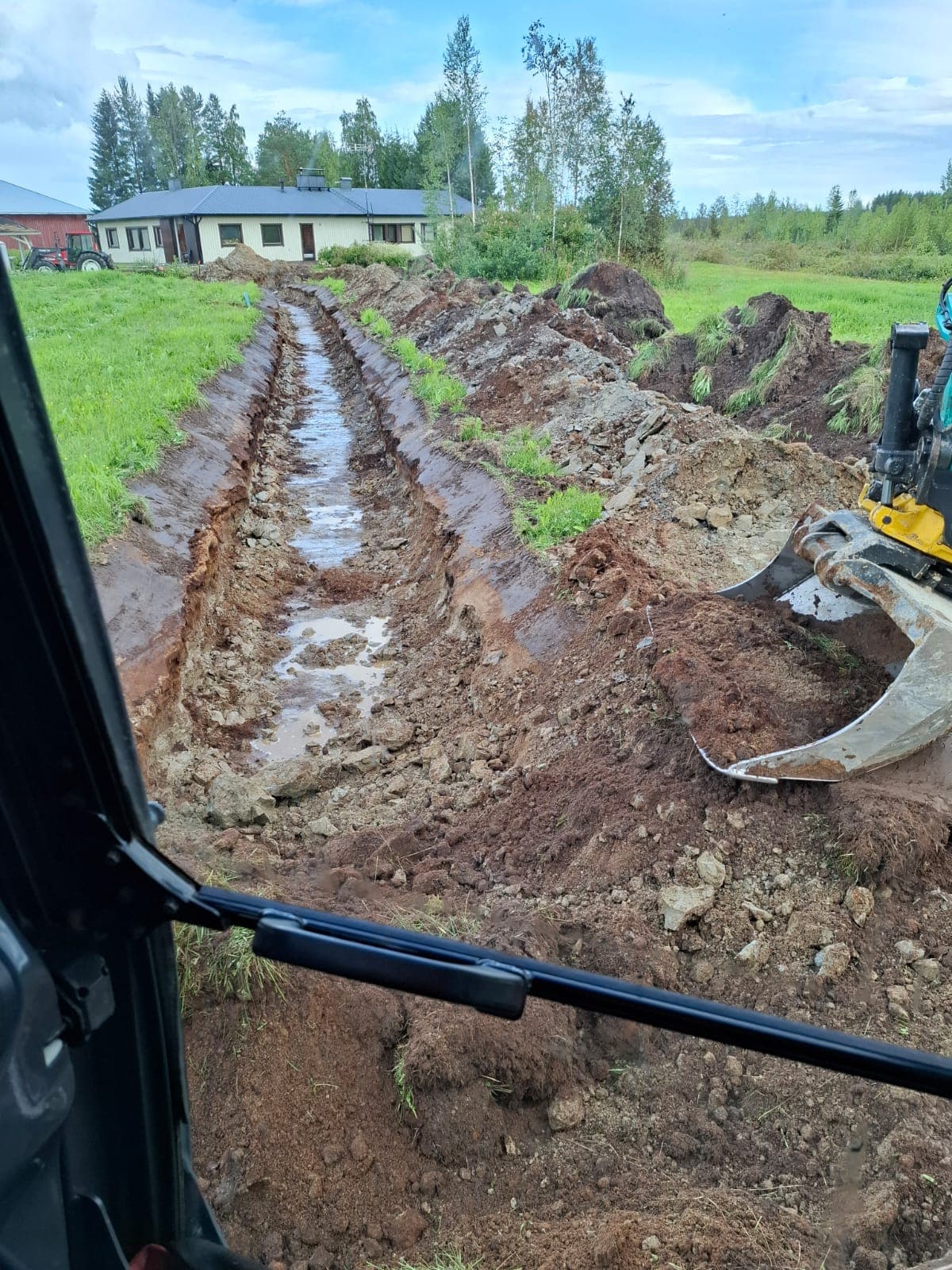 Kaivettu oja ja kaivinkoneen kauha.